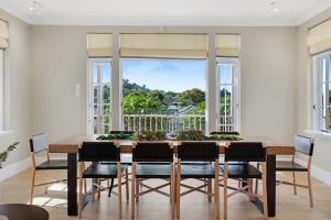 奥克兰Grande Vista 5Br Manor with Pool & Mt Eden Views的一间带桌椅和大窗户的用餐室