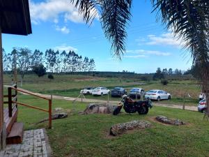 帕罗卡Fazenda Serramar的停放在有汽车停放的田野里的摩托车