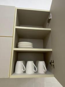 阿亚库乔Mini apartamento en Ayacucho的白色的杯子和盘子的橱柜