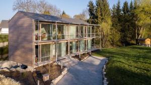 多瑙艾辛根Sportives Ökologisches Lifestyle-Ferienhaus mit großem Außenpool, Sauna und Fitnessbereich的草坪上设有玻璃窗户的大房子