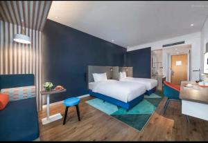 青岛青岛天一仁和智选假日酒店的卧室配有白色的床和蓝色的墙壁