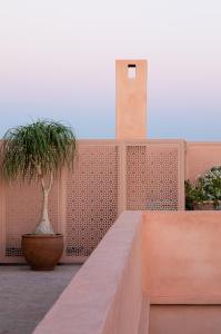 马拉喀什Riad Dar Al Dall - This Time Tomorrow in Marrakech的砖墙,两盆植物和钟楼
