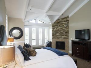 卡梅尔马车之家酒店的卧室配有一张白色大床和电视。