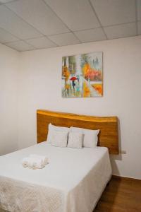拉利伯塔德Hotel Tunco Lodge的卧室配有一张白色床,墙上挂有绘画作品