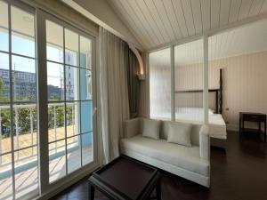 纳仲天Grand Florida芭提雅私家海滩花园公寓E206的客房设有沙发、床和窗户。