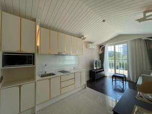 纳仲天Grand Florida芭提雅私家海滩花园公寓E206的一间带白色橱柜的厨房和一间客厅