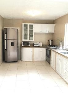 昆卡NASS Bed & Breakfast的厨房配有白色橱柜和不锈钢冰箱