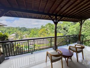 乌布The Payogan Villa Resort and Spa的设有一个配有桌椅并享有美景的阳台。