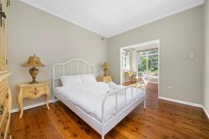 悉尼River View Oasis: Spacious 3-Bed House with Pool的卧室配有白色的床,铺有木地板