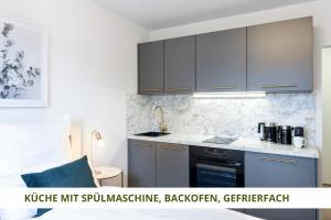 拜罗伊特Apartment Wahnfried No5 - zentrales Cityapartment Küche mit Duschbad - 300m zur Fussgängerzone的厨房配有灰色橱柜和炉灶烤箱