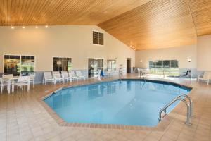 奇珀瓦福尔斯Country Inn & Suites by Radisson, Chippewa Falls, WI的大型客房的大型游泳池,配有桌椅