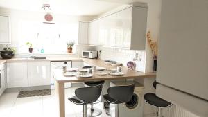 诺里奇Relaxing 3 Bedroom Norwich Haven的厨房配有白色橱柜和桌椅