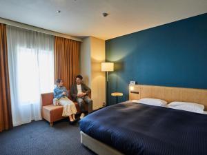 泉佐野关西机场华盛顿酒店的两名妇女坐在酒店带床的房间