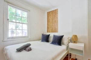 悉尼Delightful 2 Bedroom House Pyrmont 2 E-Bikes Included的一间卧室配有一张带蓝色枕头的床和一扇窗户。