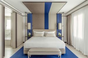 西斯蒂亚纳Tivoli Portopiccolo Sistiana Wellness Resort & Spa的一间卧室配有一张蓝色条纹的白色大床