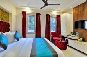 新德里Hotel Delhi Fab - Near Connaught Place的一间卧室配有床、电视和红色窗帘