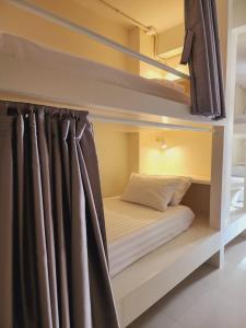曼谷Line Bangkok Hostel的双层床间内的一张床位,配有窗帘