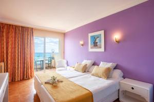 萨科马BJ Playa Blanca的酒店客房设有一张大床和紫色的墙壁