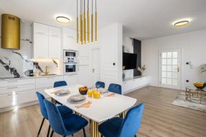 特罗吉尔VIPo Seget Apartments的厨房以及带白色桌子和蓝色椅子的用餐室。