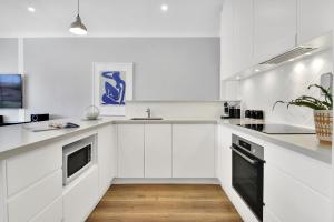 悉尼Stylish, Sunny & Spacious 2 Bedroom Apartment, Mosman的白色的厨房配有白色橱柜和黑色洗碗机