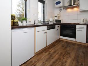 吕本Holiday home Luebben的厨房铺有木地板,配有白色橱柜。