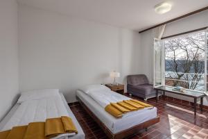 克拉列维察Uvala Scott的一间卧室设有两张床、一把椅子和一个窗户。