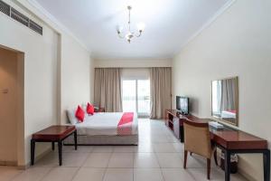 沙迦Zenith Smart Vacation Homes, Sharjah的酒店客房配有一张床、一张书桌和一台电视。
