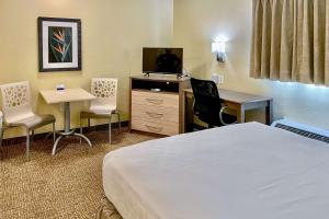 迈尔斯堡Suburban Studios Fort Myers Cape Coral的酒店客房配有一张床、一张书桌和一台电视。
