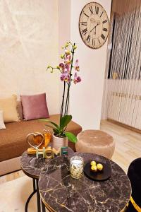 马马亚Iaki Apartment Mamaia的客厅配有桌子和墙上的时钟