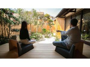 TatsunoKominka Hotel kurasu - Vacation STAY 24260v的坐在庭院椅子上的男人和女人