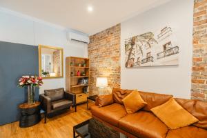 悉尼Newtown Cozy Stays的客厅配有棕色真皮沙发和椅子