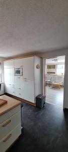 KonradsreuthFerienwohnung, Urlaub im Frankenwald的一间带白色橱柜的厨房和一间客厅