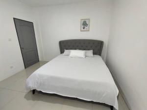 米里CASA homestay 軒名宿的白色客房内的一张床铺,配有白色床单