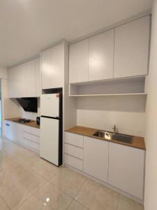 米里CASA homestay 軒名宿的厨房配有白色橱柜、水槽和冰箱。