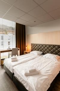 贝尔普Los Lorentes Hotel Bern Airport的一张大白色的床,位于带书桌的房间里
