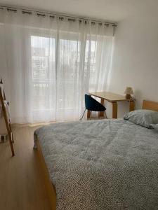 塞尔吉Bel appartement tout confort aux Portes de Paris的一间卧室配有一张床、一张桌子和一个窗户。