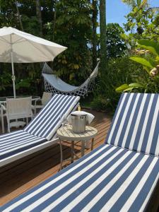 瓜鲁雅Guest House Guarujá Hotel Boutique的两张蓝白椅子和一张桌子以及一把伞