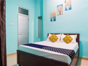 比拉斯布尔OYO Hotel Hanu Inn的一间卧室拥有蓝色的墙壁,配有一张带黄色枕头的床。