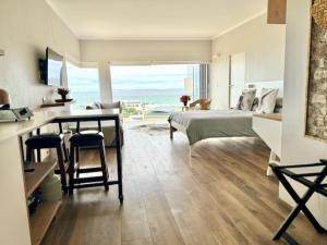 开普敦Small Bay Beach Suites的一间卧室配有一张床、一张桌子和一张桌子