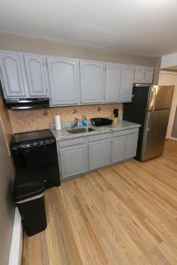 泽西市2-Bed Stylish Space mins to NYC的厨房配有白色橱柜、水槽和冰箱。