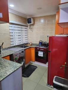拉各斯Kings Lux Home的厨房配有炉灶和红色冰箱。