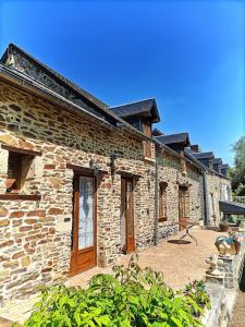 CahagnesLe Moulin de Benneville chambres d'hôtes, petit déjeuner compris的一座石头建筑,前面设有庭院