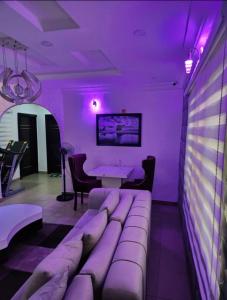 拉各斯Kings Lux Home的紫色的客房配有一张沙发和一张桌子