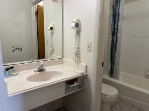 弗雷德里克斯堡落日套房汽车旅馆的一间带水槽、镜子和卫生间的浴室