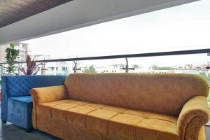 浦那OYO Collection O Hotel Rk Inn的一张棕色沙发,位于带大窗户的房间里