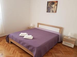 帕格Apartments and rooms Iva的一间卧室配有一张紫色床和两条毛巾
