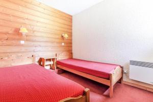 瓦尔莫雷尔Quartier Crève Cœur - maeva Home - Duplex 3 Pièces 8 Personnes Confort 03的一间卧室设有红色的床和木墙