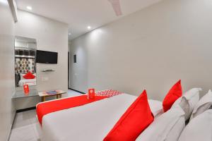 拉杰果德OYO Nova Hotel Nildeep的卧室配有带红色枕头的大型白色床