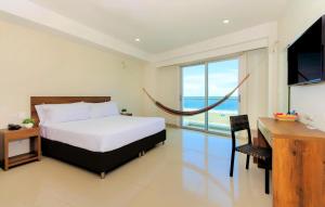 卡塔赫纳海滨夏日酒店的一间卧室配有一张床、一张书桌和一台电视