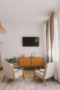 维拉多比斯坡Pure Fonte Velha B&B的客厅配有两把椅子和墙上的电视